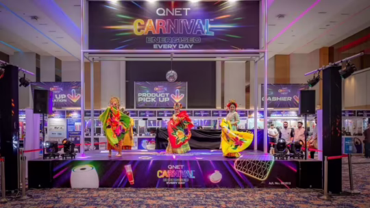 три девушки в сценических костюмах на сцене QNET Carnival 