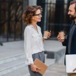 сильный инструмент продаж - молодые парень и девушка на улице ведут деловую беседу с кофе в руках